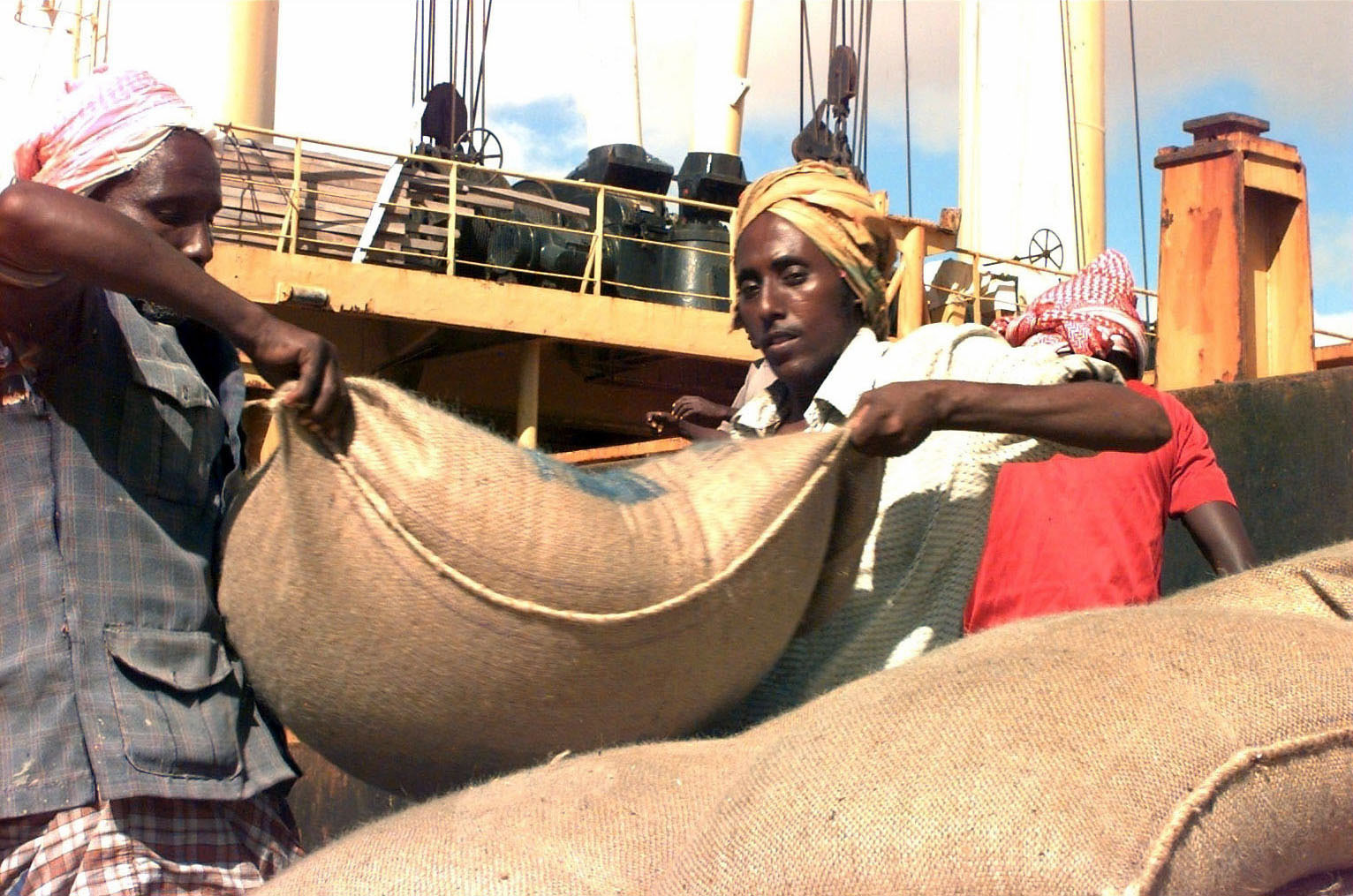 Somali workers unload a ship carrying sacks of wheat