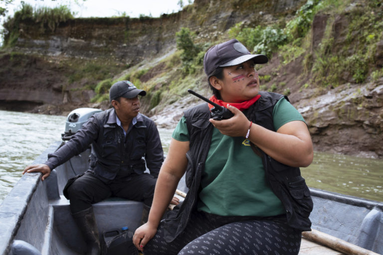 Alexandra Narváez and Holger Quenamá travel on the Aguarico River in a boat belonging to the Sinangoe Indigenous Guard.
