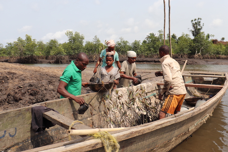 Community members load up a canoe to transport seedlings for planting. Image by Orji Sunday for Mongabay.