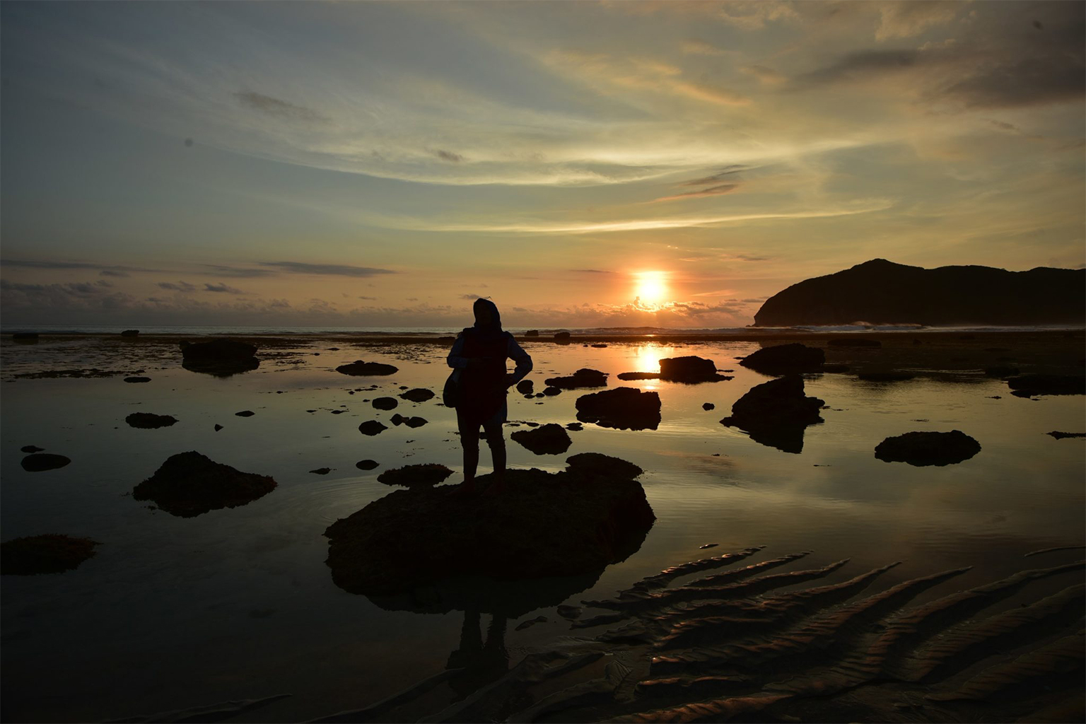 A tourist enjoys the sunset at Lawar Beach in West Sumbawa. 
