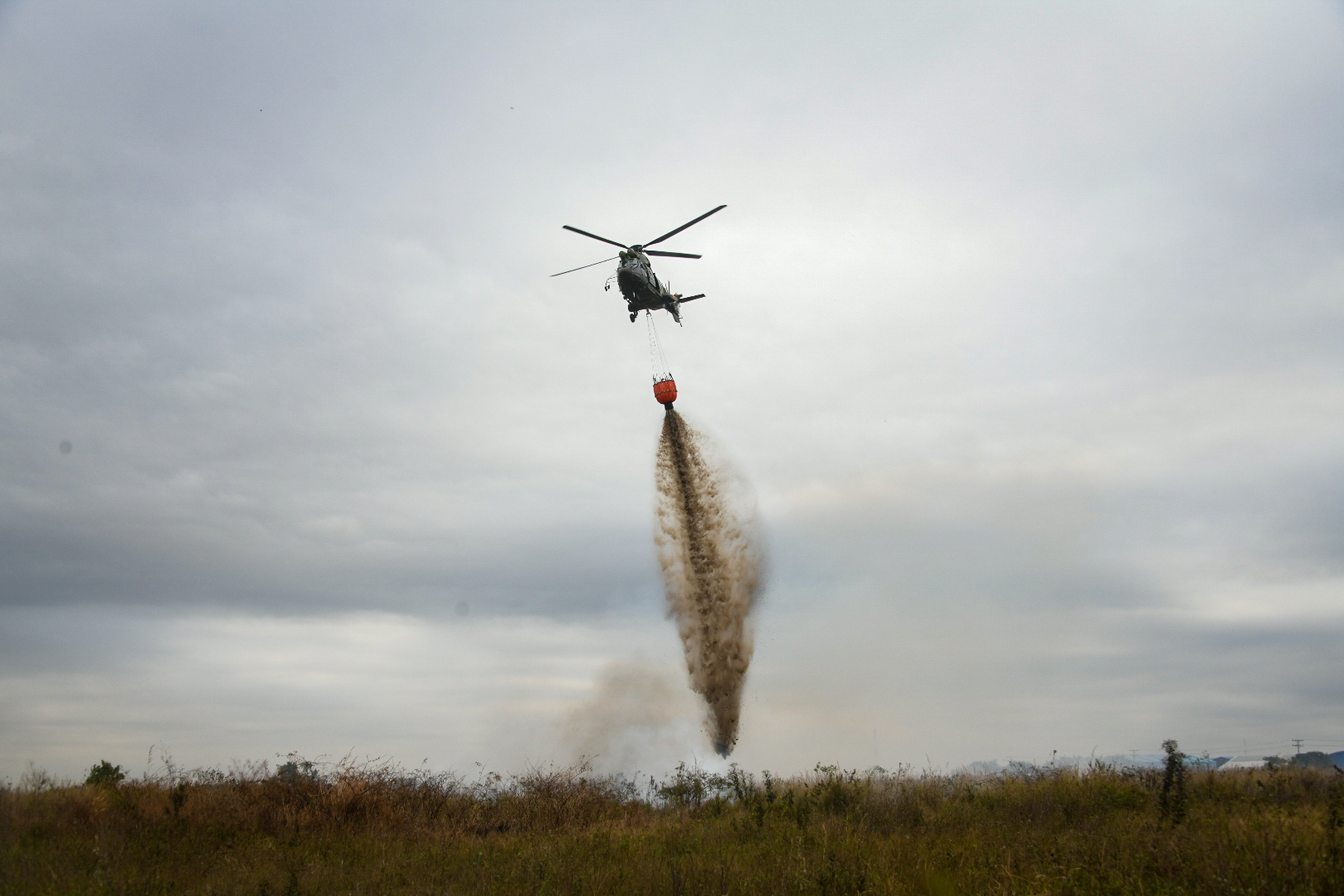 A helicopter drops a load of water on a fire. Image courtesy of the Bolivian Ministry of Defense.