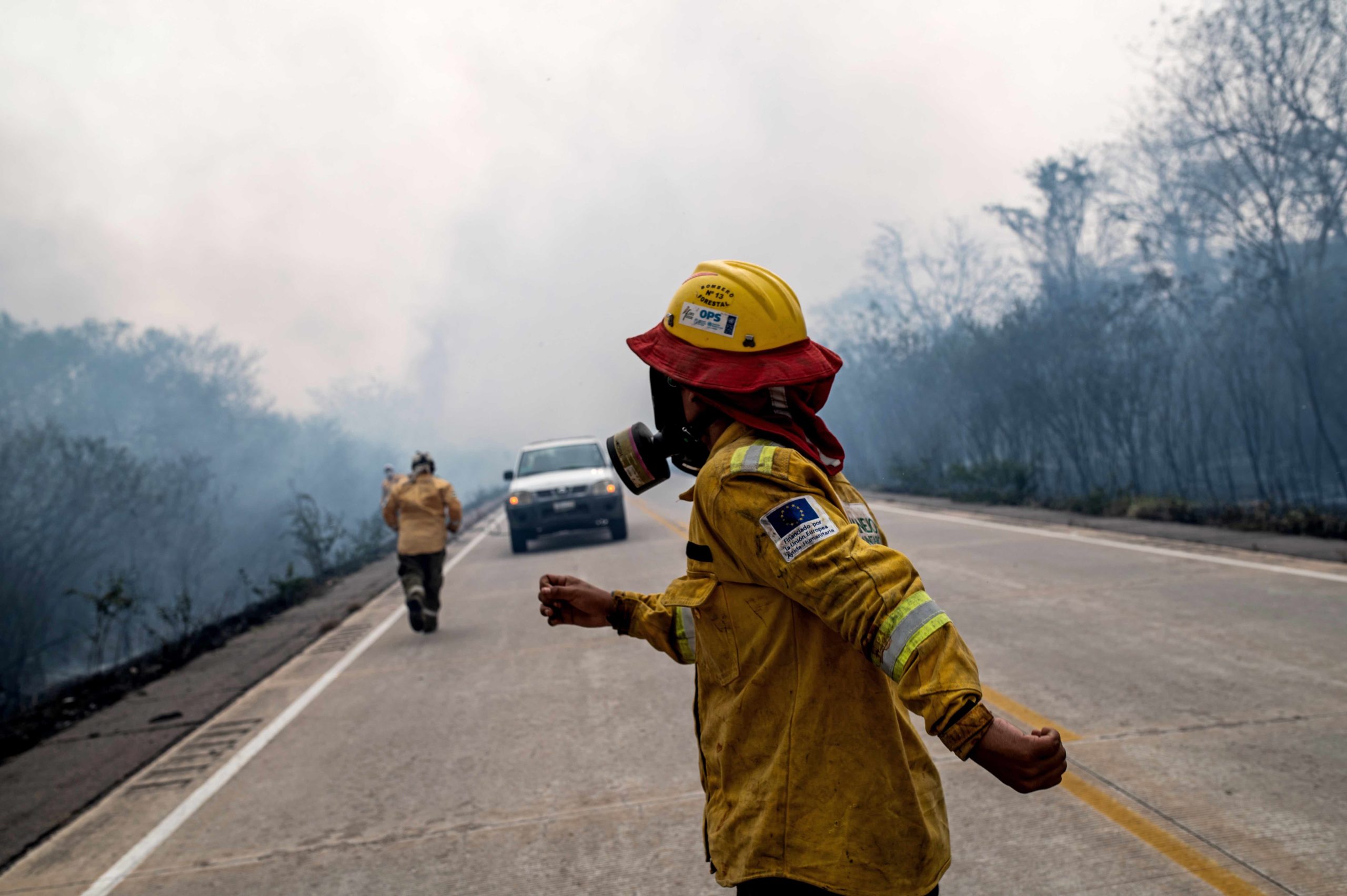 Firefighters race to stop a fire advancing along a highway in southern Bolivia's Chiquitania region. Image by Claudia Belaunde.