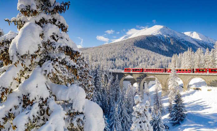 Bernina Express train in the forest covered with snow, Switzerland